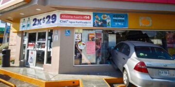 Automóvil gris Chevrolet Aveo incrustado en la fachada de una tienda de conveniencia